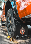 Car wheel with a black tire mud flaps branded 'Flappes' on a road.