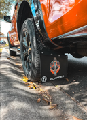 Close-up of a premium Flappies custom mudflap showing printed design, durable material, and mounting behind a 4WD wheel